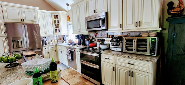 149 Oak, Cresco, PA 18326 - kitchen featuring appliances with stainless steel finishes, cream cabinets, lofted ceiling, tasteful backsplash, and light stone counters