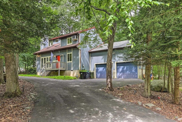 348 Fernwood Dr, East Stroudsburg, PA 18301 - view of front facade with asphalt driveway, a garage, an AC wall unit, and a chimney