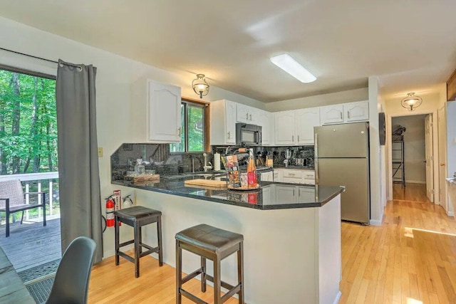 348 Fernwood Dr, East Stroudsburg, PA 18301 - kitchen with freestanding refrigerator, black microwave, a peninsula, white cabinetry, and dark countertops