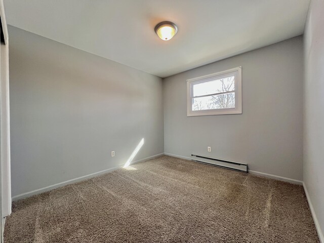 carpeted empty room with a baseboard heating unit and baseboards