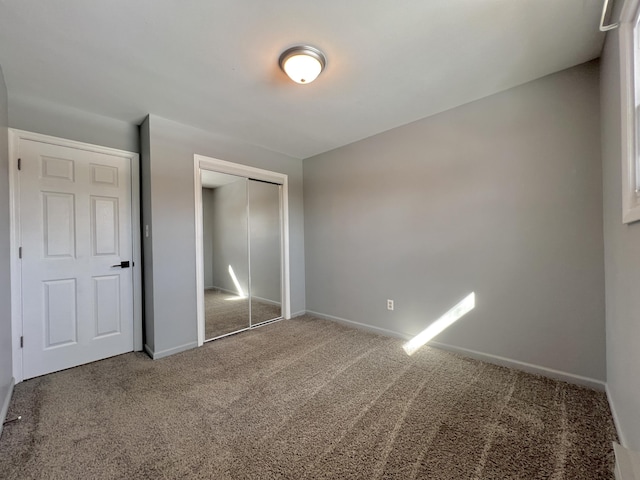unfurnished bedroom with carpet flooring, a closet, and baseboards