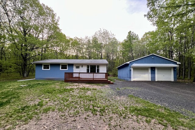 single story home with a garage, a wooden deck, an outdoor structure, and view of scattered trees