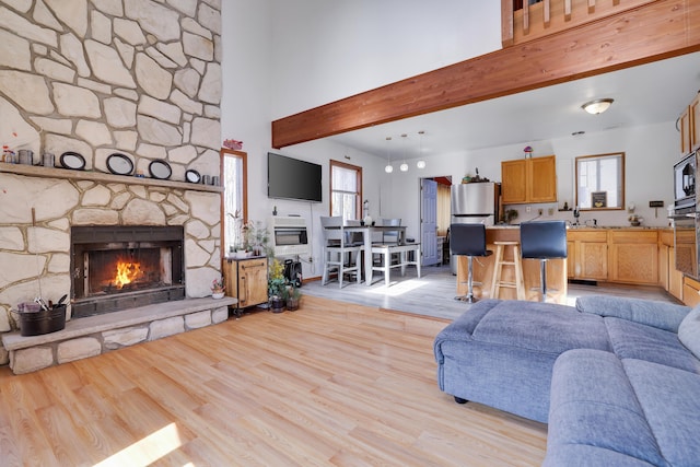 1239 Mink Trl, Bushkill, PA 18324 - living area featuring a stone fireplace, a healthy amount of sunlight, light wood-type flooring, and a high ceiling