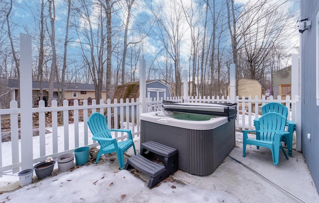 view of patio with a hot tub, fence, a storage unit, and an outdoor structure