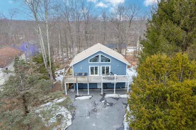 back of property with stairway, a deck, and a view of trees