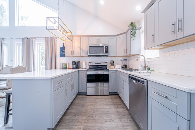 kitchen featuring a breakfast bar area, a peninsula, stainless steel appliances, light wood-style floors, and a sink