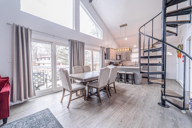 dining room with high vaulted ceiling and light wood finished floors