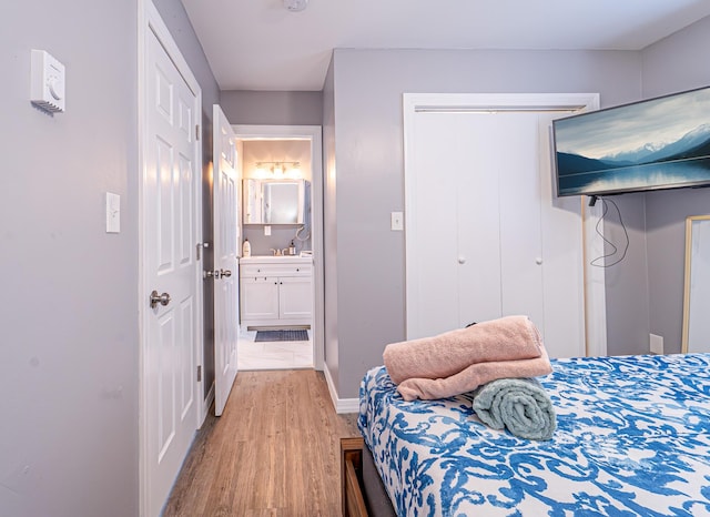 bedroom with light wood-style flooring, baseboards, a closet, and ensuite bathroom