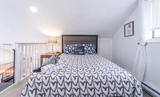 bedroom with lofted ceiling, a textured ceiling, baseboard heating, and wood finished floors