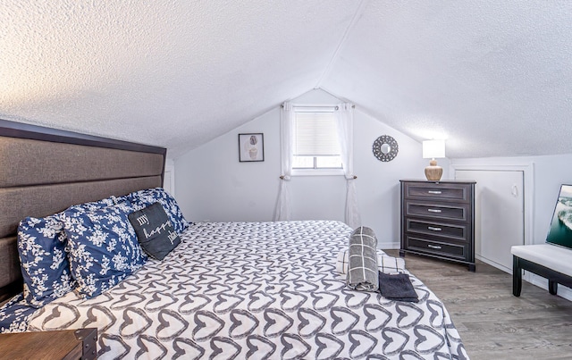 bedroom featuring vaulted ceiling, a textured ceiling, and wood finished floors