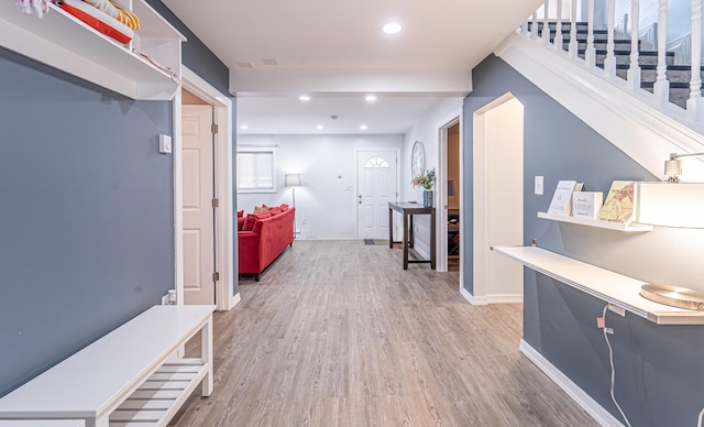 hallway with recessed lighting, baseboards, stairway, and light wood finished floors