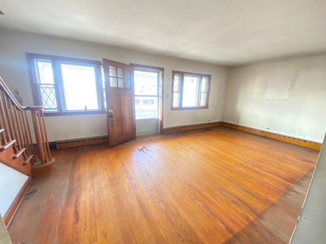 interior space with plenty of natural light, a baseboard radiator, stairway, and wood finished floors