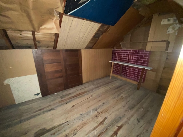 additional living space featuring lofted ceiling, wood walls, and wood finished floors