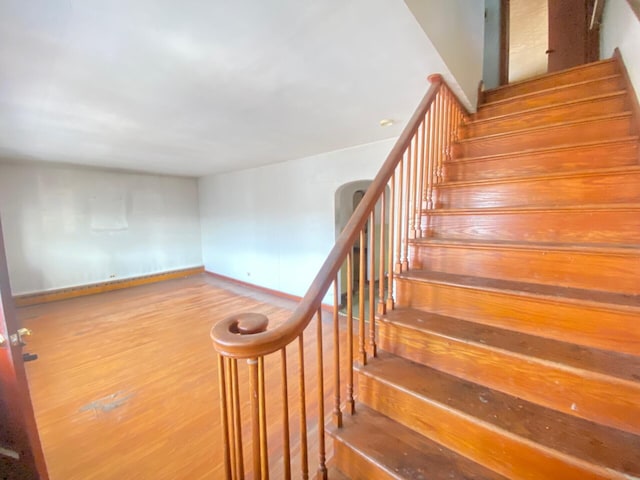 staircase featuring wood finished floors and baseboards