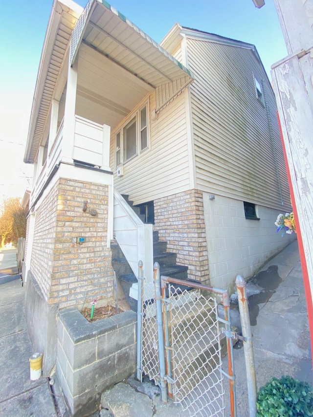 view of property exterior featuring a gate, brick siding, and fence