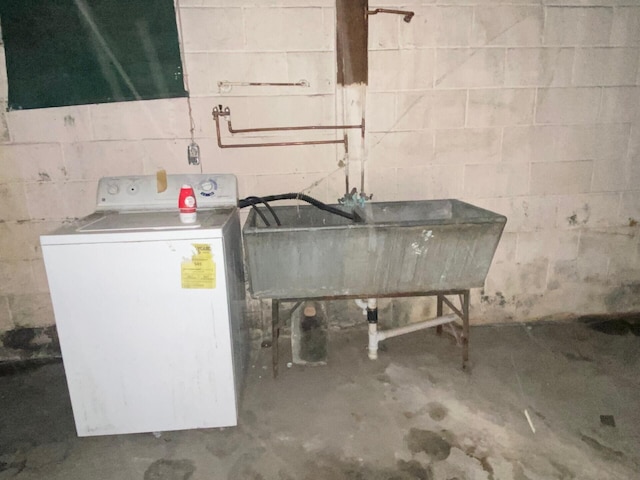 below grade area with a sink, washer / dryer, and concrete block wall