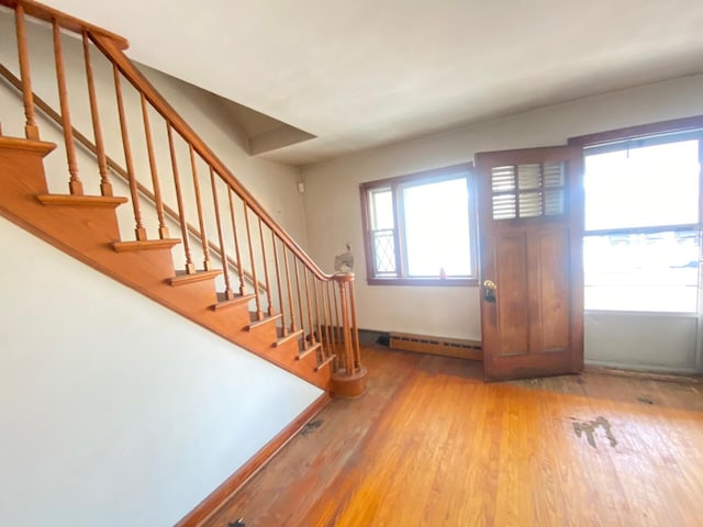 entryway featuring baseboards, stairway, baseboard heating, and wood finished floors