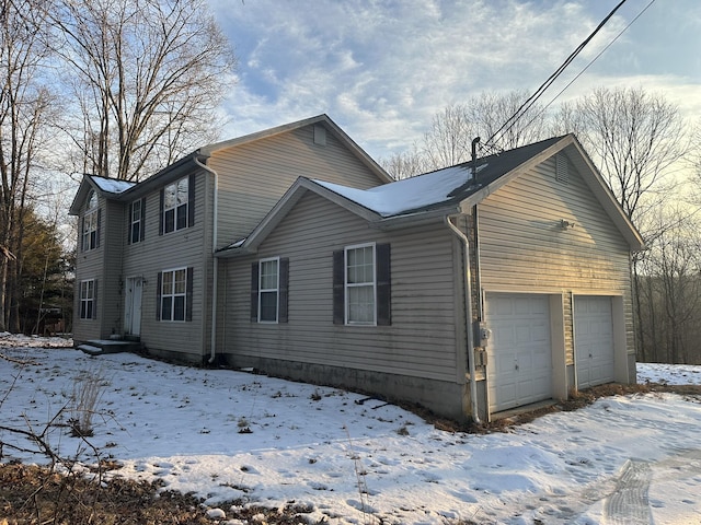 snow covered property with an attached garage