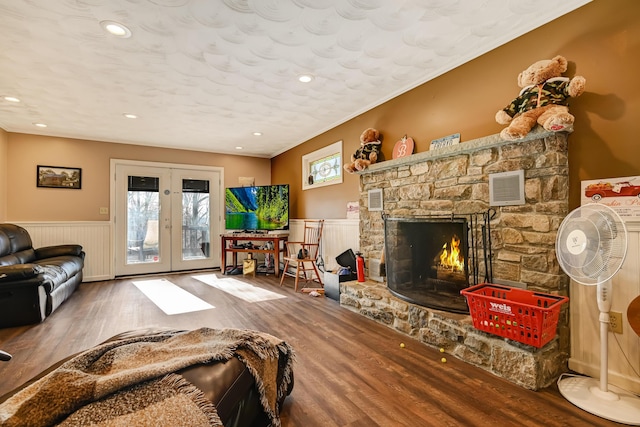 154 Elgin Way, Bushkill, PA 18324 - living area featuring visible vents, wood finished floors, a stone fireplace, a wainscoted wall, and french doors