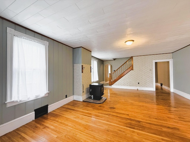233 Lafayette Ave, Palmerton, PA 18071 - unfurnished living room with light wood-type flooring, arched walkways, a wood stove, brick wall, and crown molding