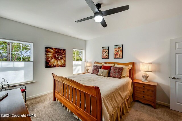 carpeted bedroom featuring ceiling fan, multiple windows, and baseboards