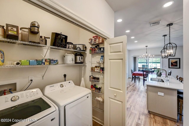 laundry room with laundry area, separate washer and dryer, a sink, visible vents, and light wood-type flooring