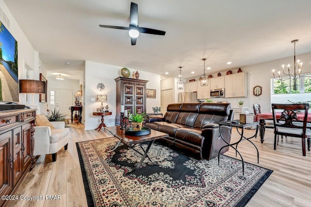 living area featuring recessed lighting, light wood-style flooring, and ceiling fan with notable chandelier