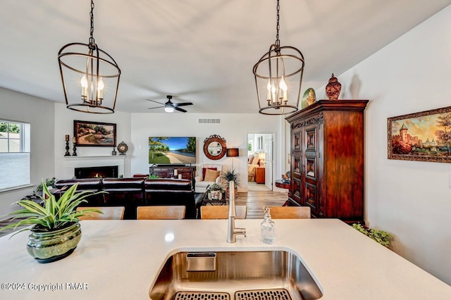 kitchen featuring a warm lit fireplace, a chandelier, visible vents, light countertops, and decorative light fixtures