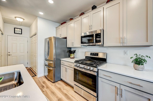 kitchen with appliances with stainless steel finishes, light countertops, and light wood finished floors