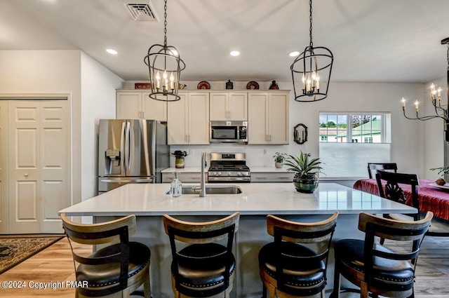 kitchen with light wood-type flooring, a breakfast bar, a center island with sink, and stainless steel appliances