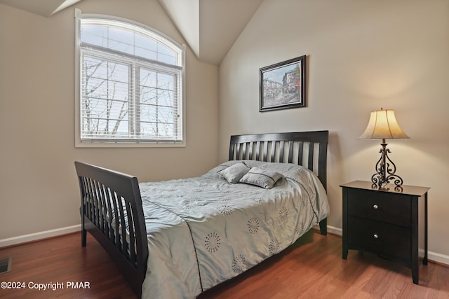 bedroom featuring visible vents, baseboards, vaulted ceiling, and wood finished floors