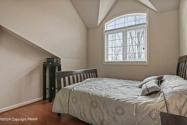 bedroom with baseboards, vaulted ceiling, and wood finished floors