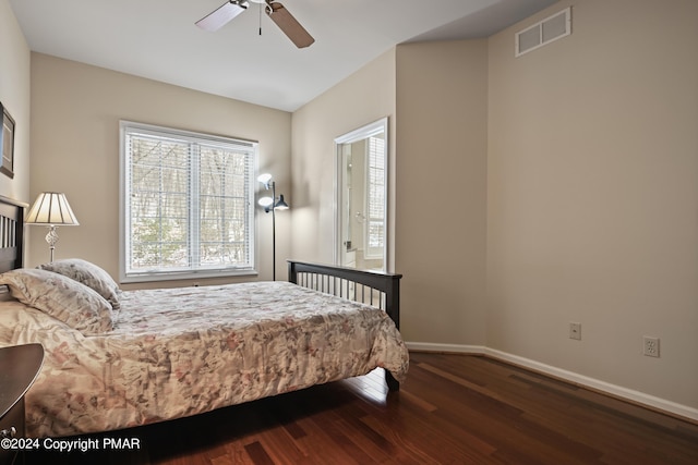 bedroom with a ceiling fan, wood finished floors, visible vents, and baseboards