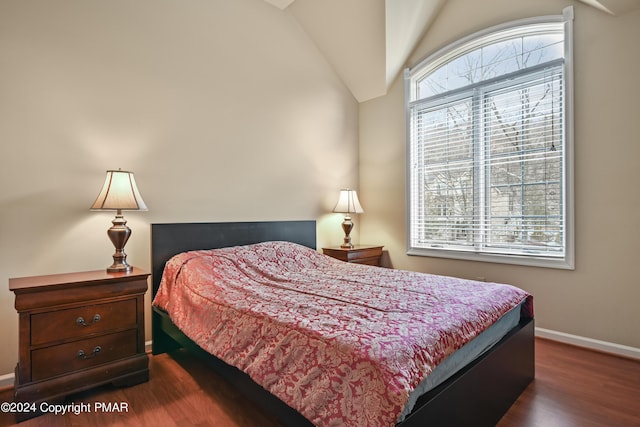 bedroom with multiple windows, baseboards, vaulted ceiling, and wood finished floors