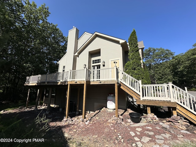 view of property exterior featuring stairway, a chimney, and a wooden deck