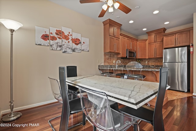 kitchen with stone counters, a breakfast bar, appliances with stainless steel finishes, decorative backsplash, and brown cabinets