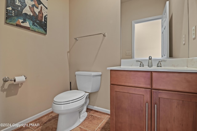 bathroom featuring toilet, baseboards, and vanity