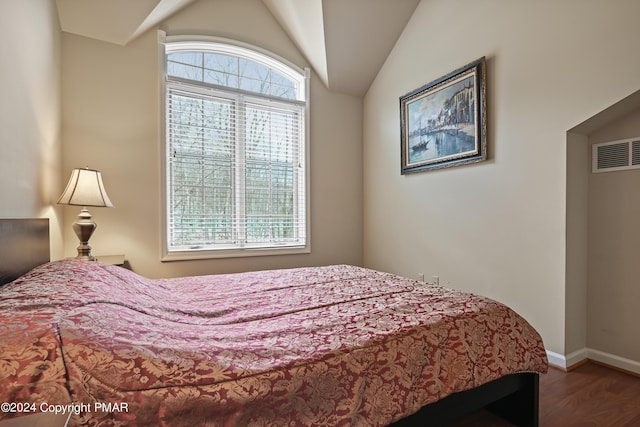 bedroom featuring lofted ceiling, wood finished floors, visible vents, and baseboards