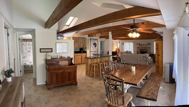 kitchen with stacked washer / dryer, open floor plan, beamed ceiling, a fireplace, and a sink