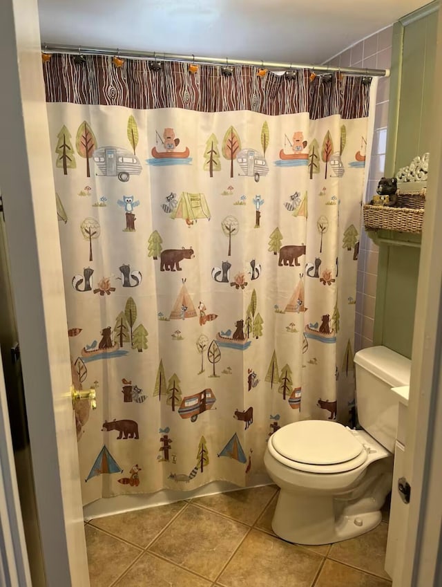 bathroom featuring a shower with shower curtain, toilet, and tile patterned floors