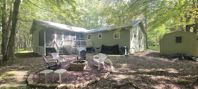 rear view of house featuring an outdoor fire pit, a sunroom, a wooden deck, a shed, and an outdoor structure