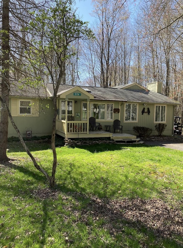 single story home featuring a deck, a front yard, and a chimney