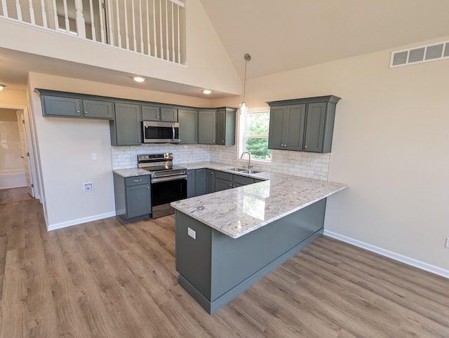 251 Bellingham Dr, Bushkill, PA 18324 - kitchen featuring appliances with stainless steel finishes, a peninsula, light wood-type flooring, decorative backsplash, and high vaulted ceiling