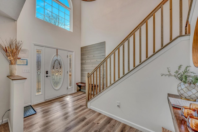 foyer with stairway, baseboards, wood finished floors, and a towering ceiling