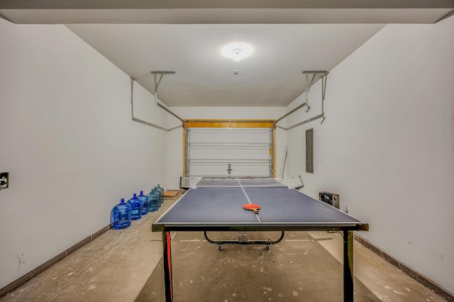 recreation room featuring electric panel, a garage, unfinished concrete floors, and baseboards