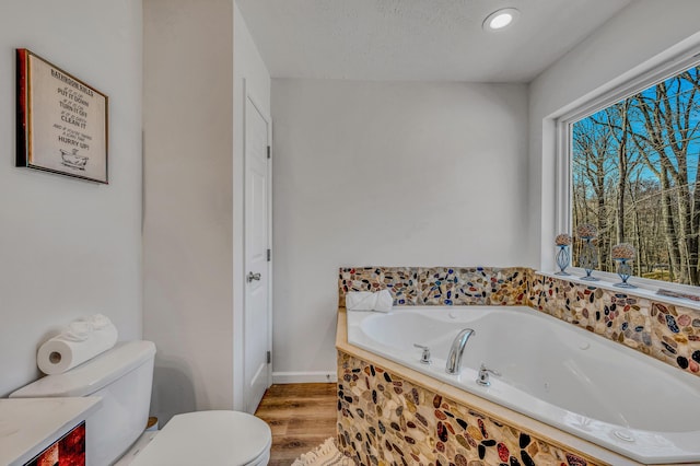 bathroom with toilet, a garden tub, recessed lighting, wood finished floors, and a textured ceiling