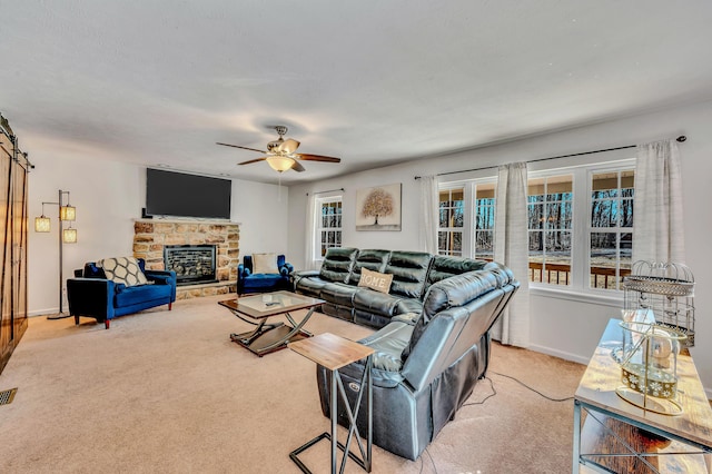 living area with visible vents, baseboards, ceiling fan, light colored carpet, and a stone fireplace