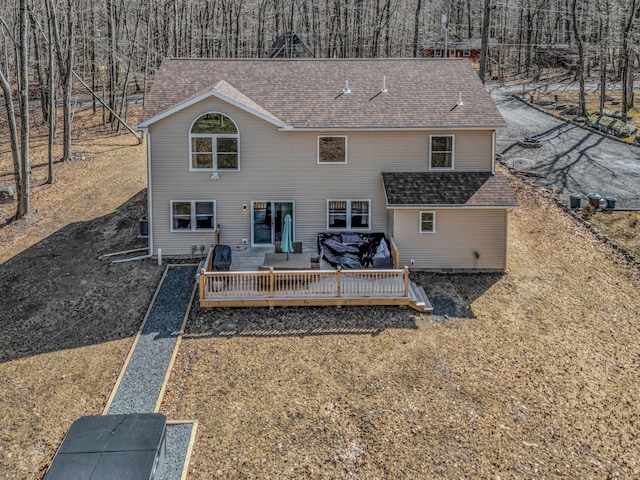 back of property featuring a deck and roof with shingles