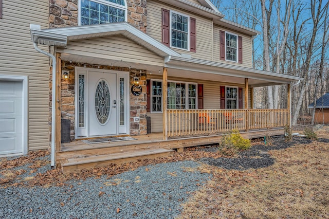 property entrance featuring a garage, stone siding, and covered porch