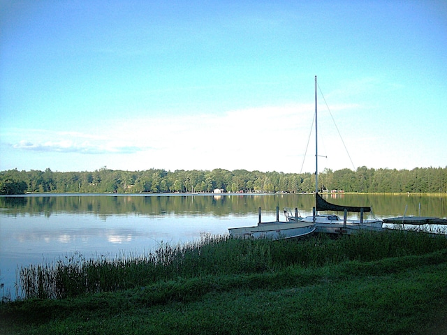 view of dock featuring a wooded view and a water view